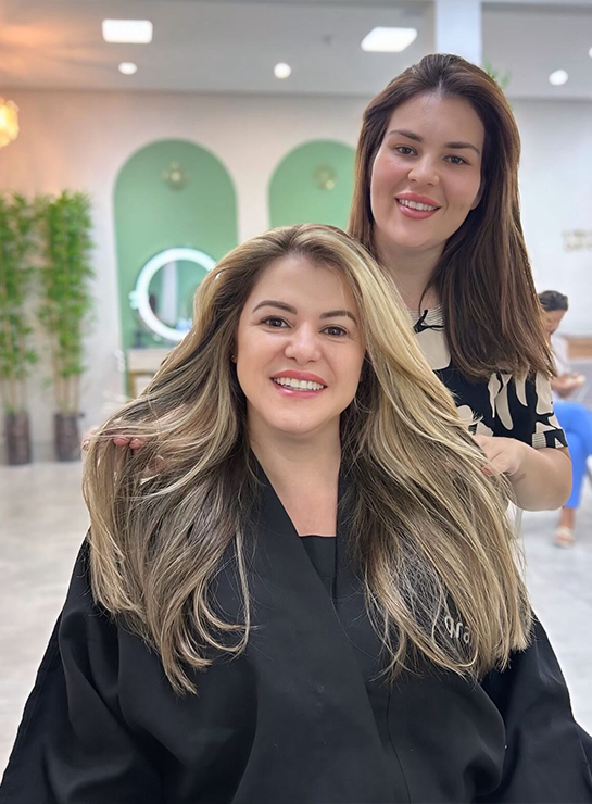 Cliente com loiro iluminado finalizado ao lado da profissional